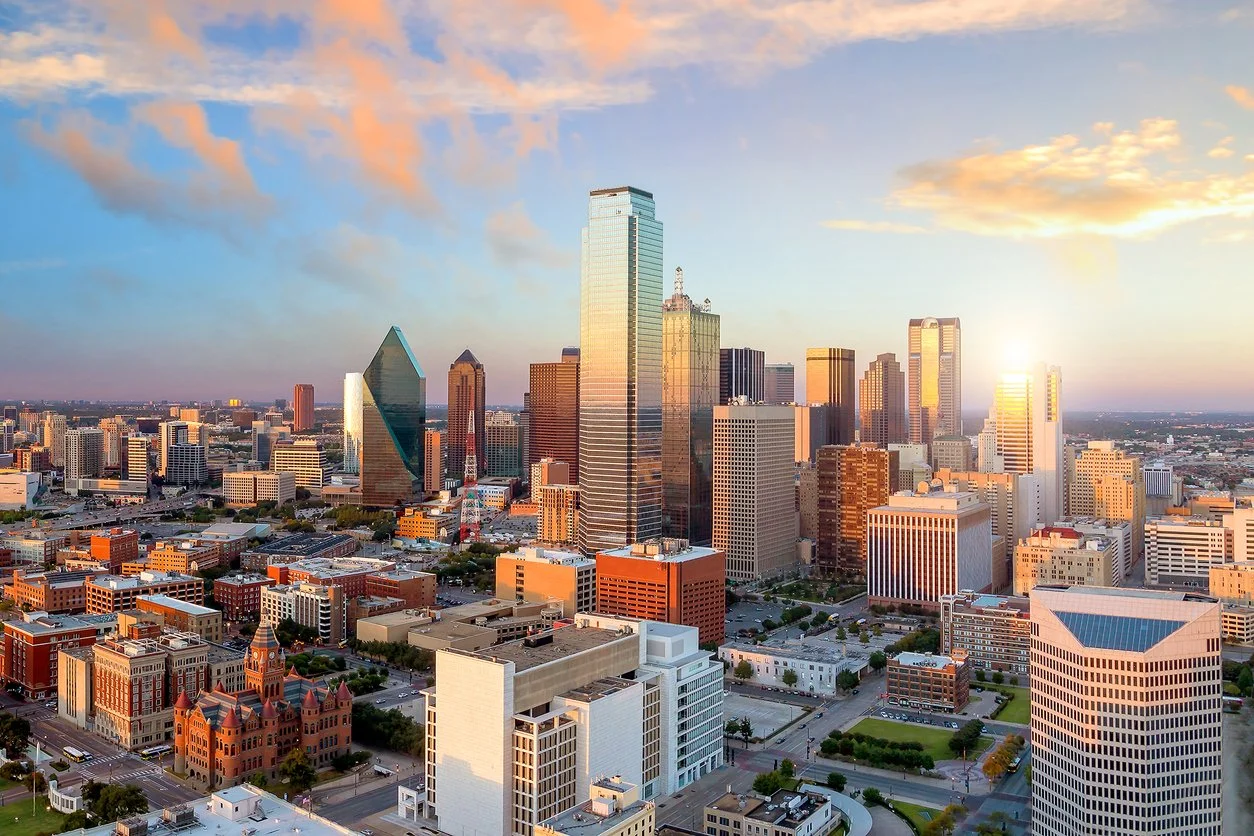 Skyline of Dallas city with tall skyscrapers during sunset.