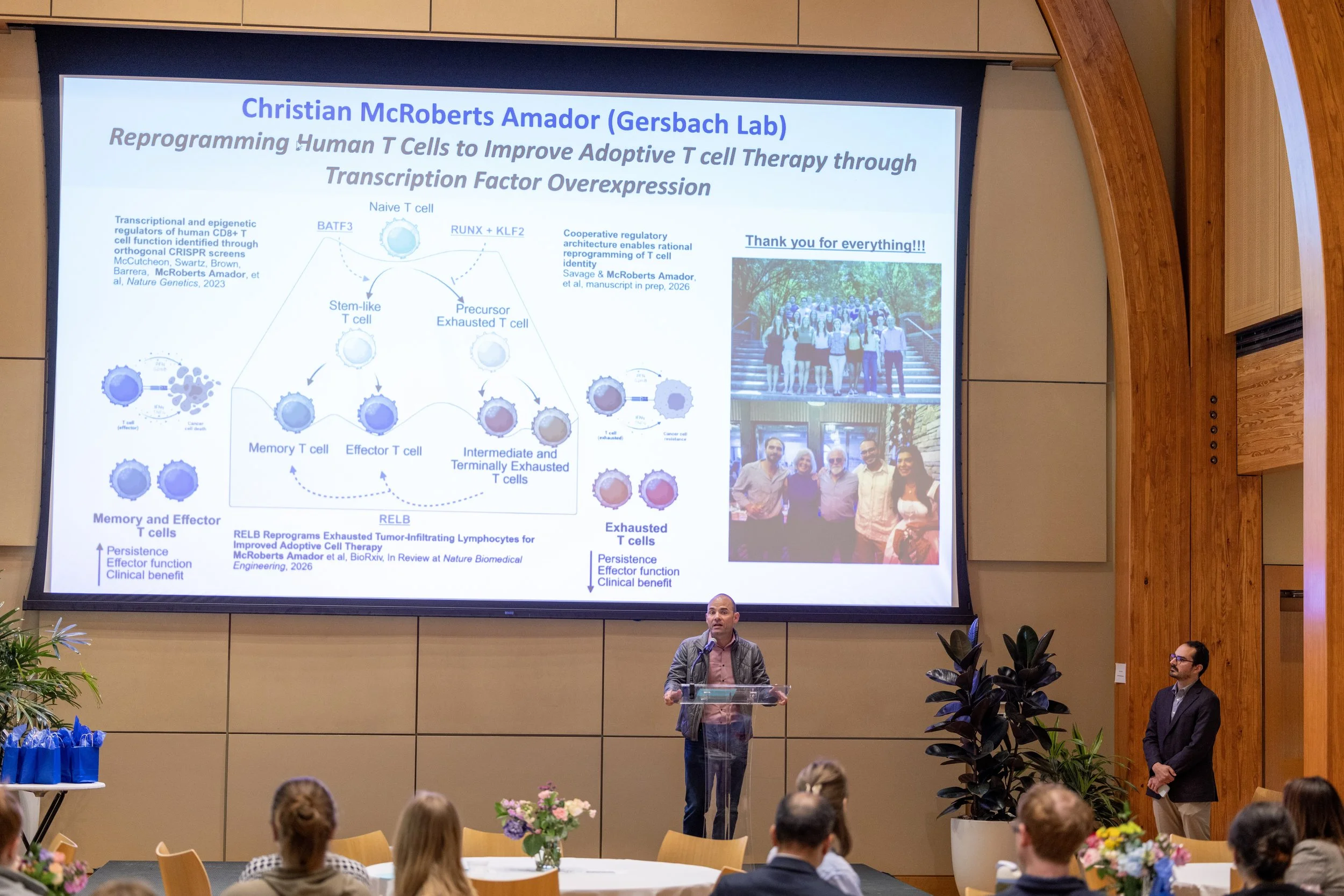 Charlie speaking at the podium in front of a summary slide of Christian's research.