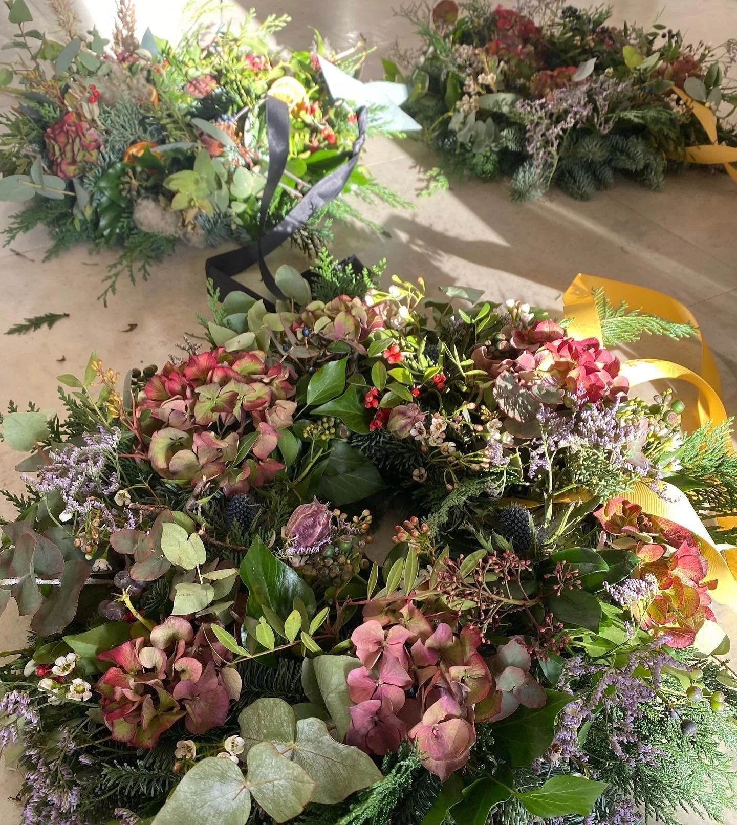 A seasonal christmas wreath filled with hydrangea, berries and colourful flowers with seasonal foliage and tied with ribbon