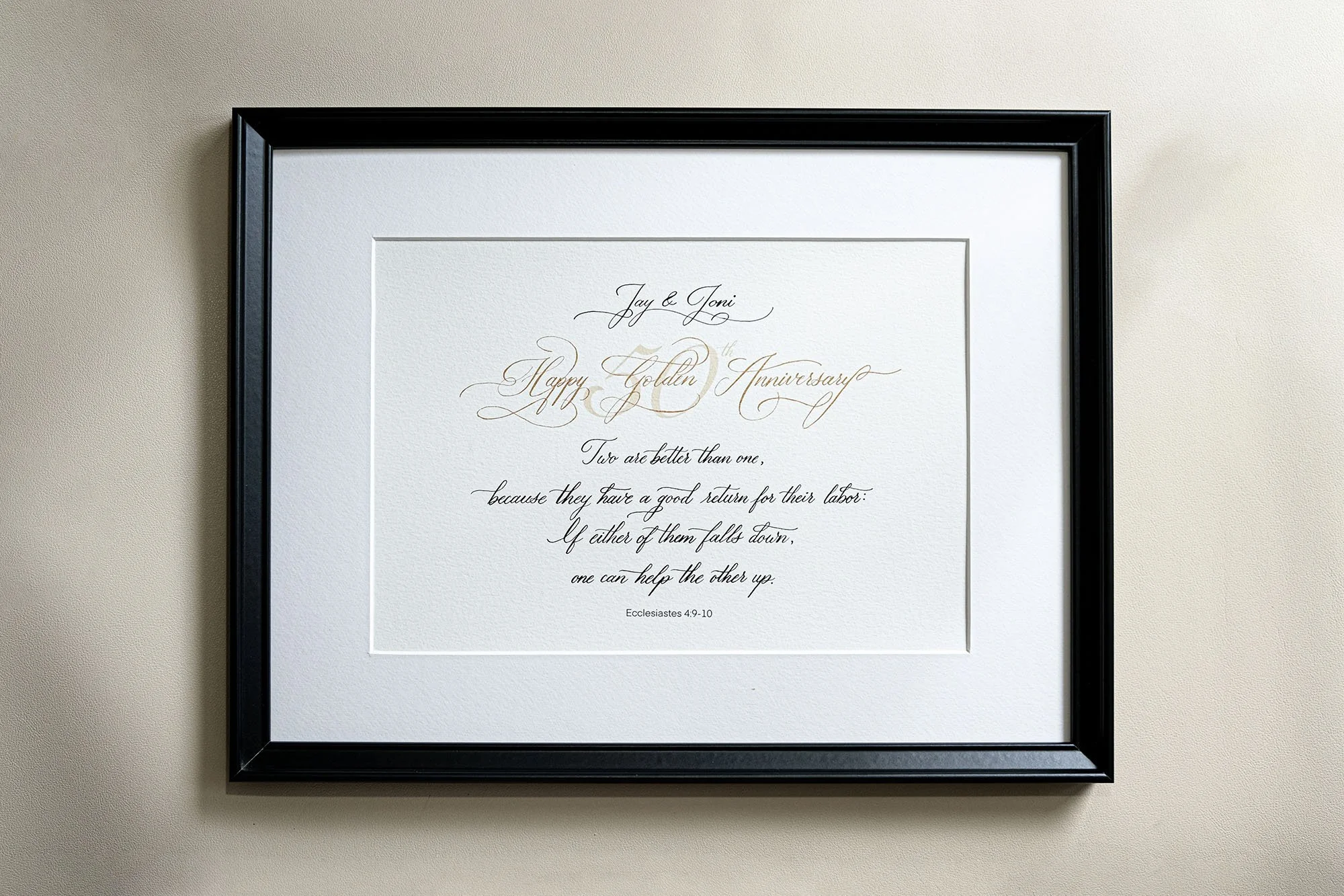 Gerahmtes kalligrafisches Kunstwerk mit glückwunschtext zur goldenen Hochzeit und Bibelzitat, schwarz umrandet auf beigem Hintergrund.