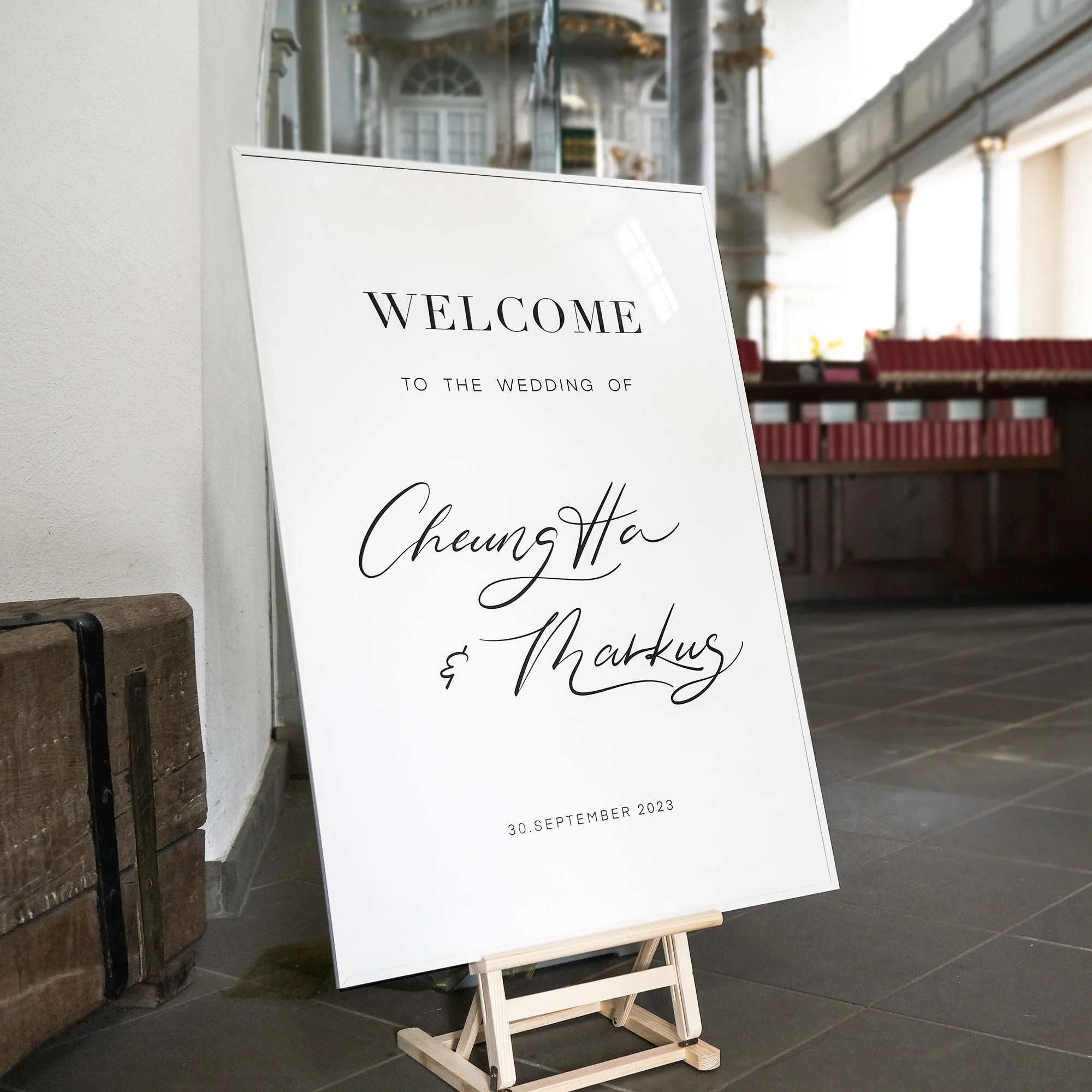 Hochzeitsschild in einer Kirche mit der Aufschrift 'Welcome to the wedding of Cheung Ha & Markus', datiert auf den 30. September 2023.