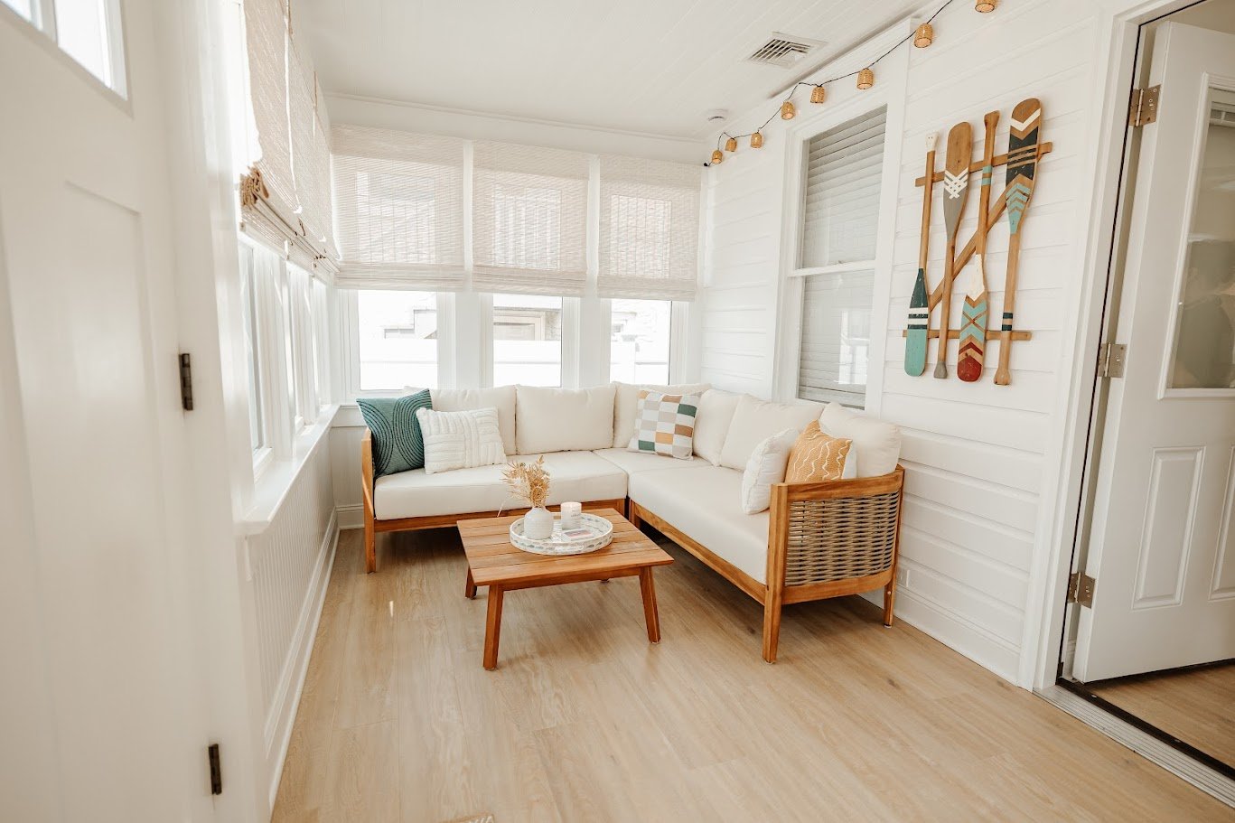 Light-filled sunroom with neutral seating, woven textures, and bright windows