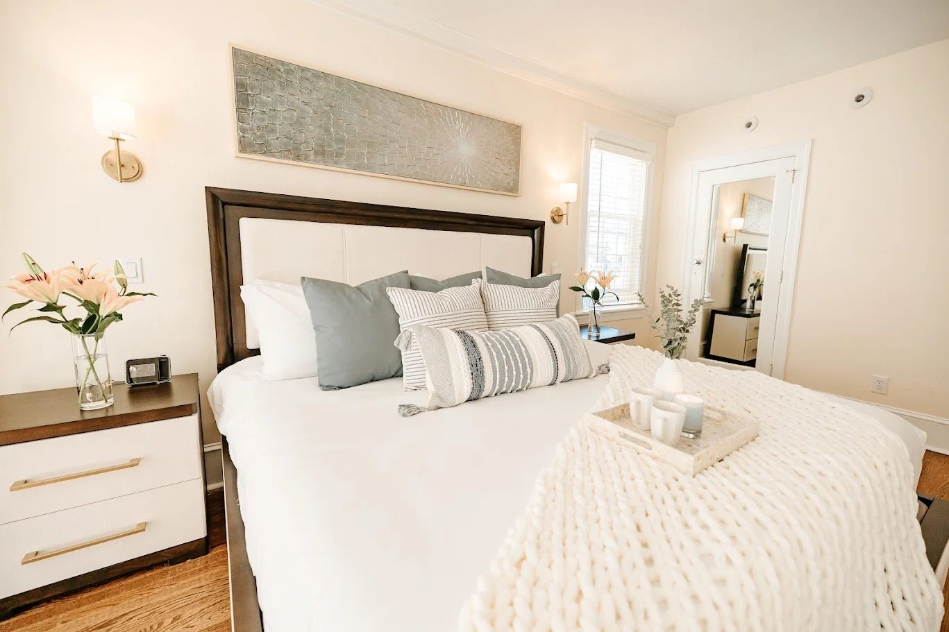 Neutral bedroom with layered bedding, wood nightstands, and soft coastal decor