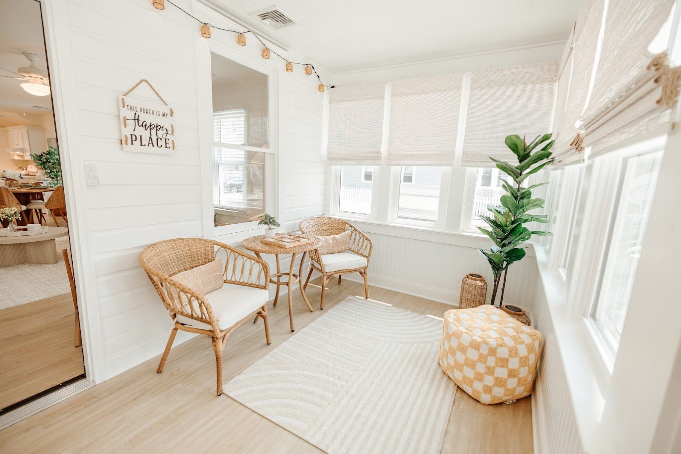 Cozy sunroom seating nook with woven chairs, round rattan table, neutral pillows, and bright natural light