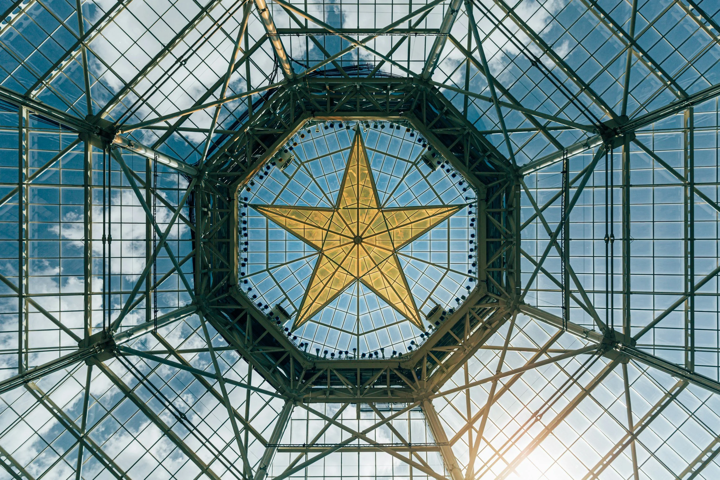 Golden Texas star suspended beneath the signature glass atrium ceiling at Gaylord Texan Resort in Grapevine, Texas.