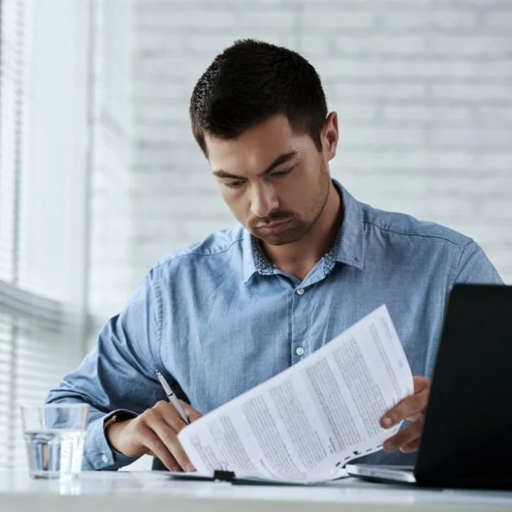 Man in blue shirt focused on reading and marking printed documents