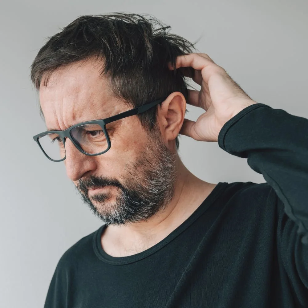 Middle-aged man with ADHD scratching head looking overwhelmed