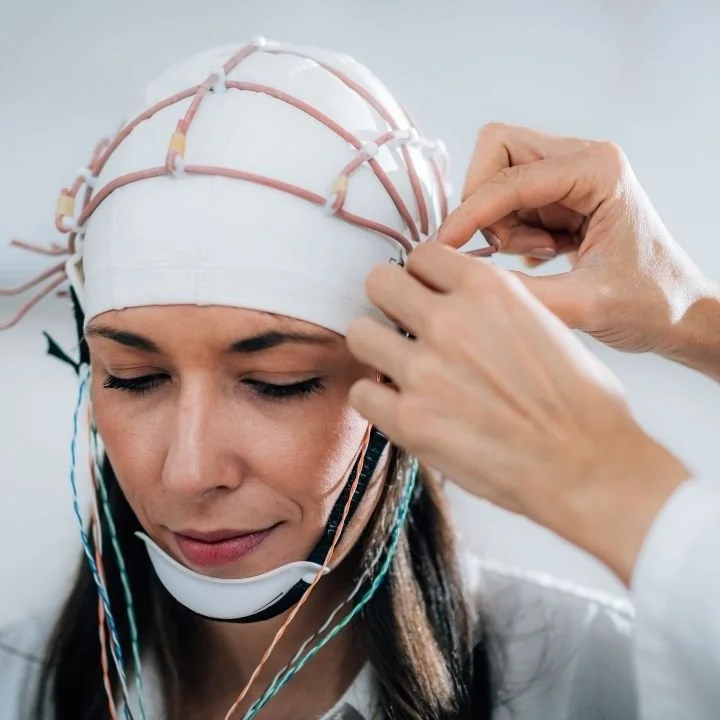 Adult woman wearing EEG cap during cognitive research assessment session.