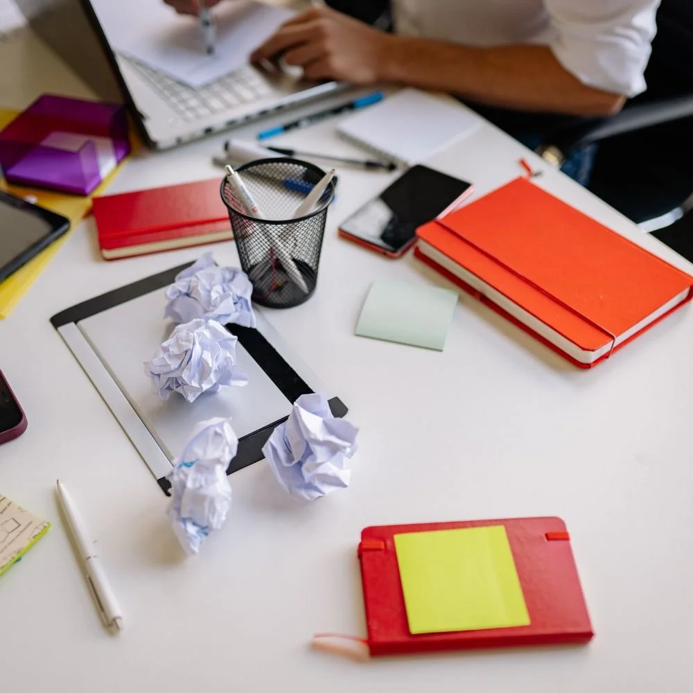 Messy desk with crumpled papers and notebooks