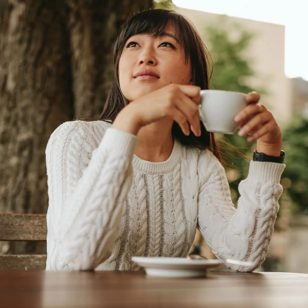 Woman drinking coffee looking thoughtful and relaxed