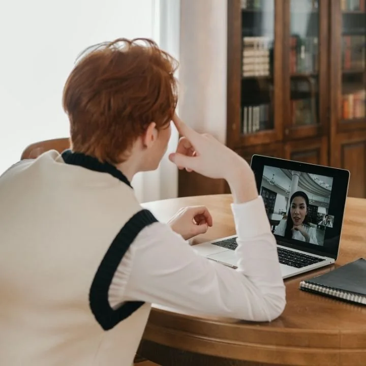Young adult participating in a virtual telehealth psychology session on a laptop at home.