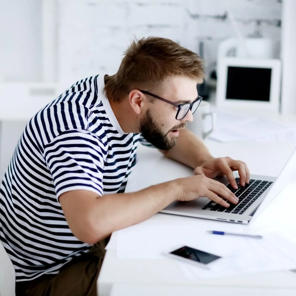 Man intensely focused on laptop screen leaning forward