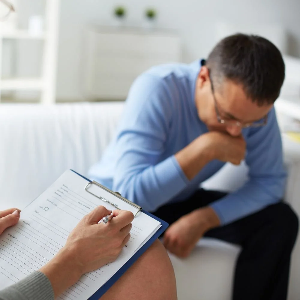 Therapist writing notes as patient looks down