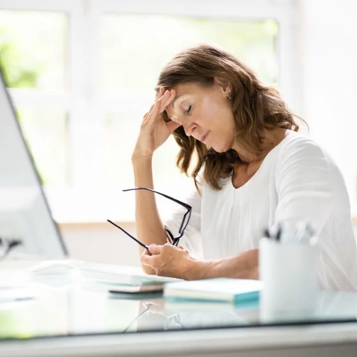 Woman feeling mentally overwhelmed at her desk, illustrating ADHD-related focus and cognitive fatigue.