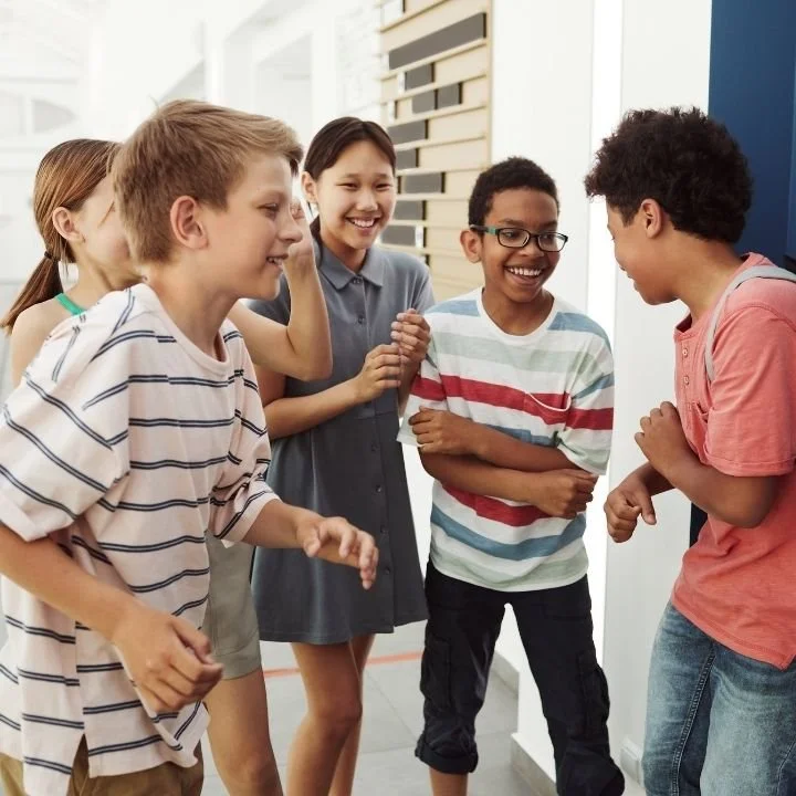 Group of children laughing together in hallway during social interaction.
