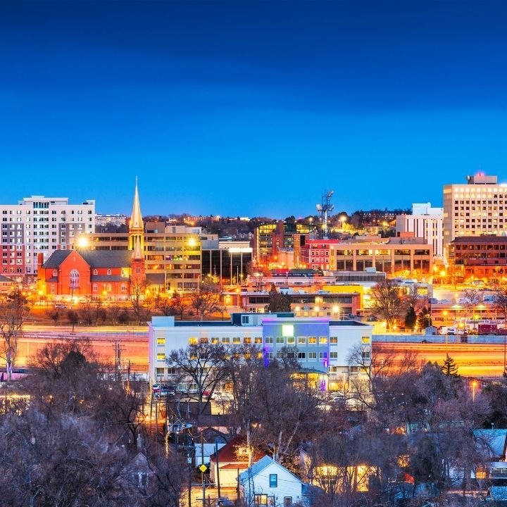Evening Colorado Spring's skyline with illuminated buildings and streets.