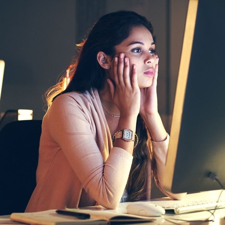 Woman staring at a computer screen while becoming distracted from her work.