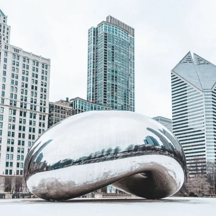 Cloud Gate sculpture in Millennium Park with downtown Chicago buildings in the background.