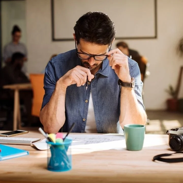Adult man reading documents at desk, concentrating deeply on work.