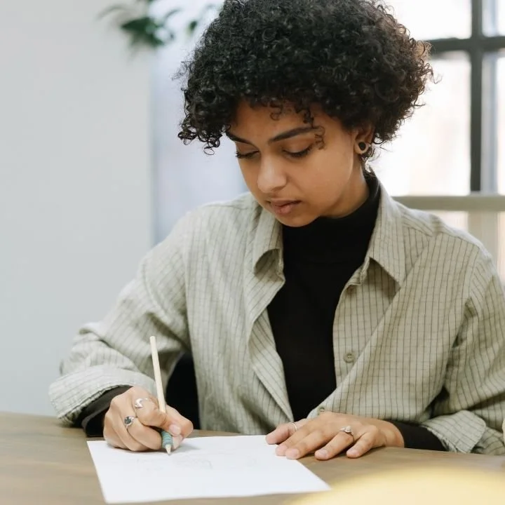 Woman writing on assessment form at desk