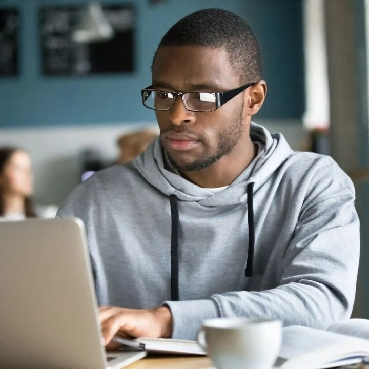 Man typing on a laptop while maintaining concentration.