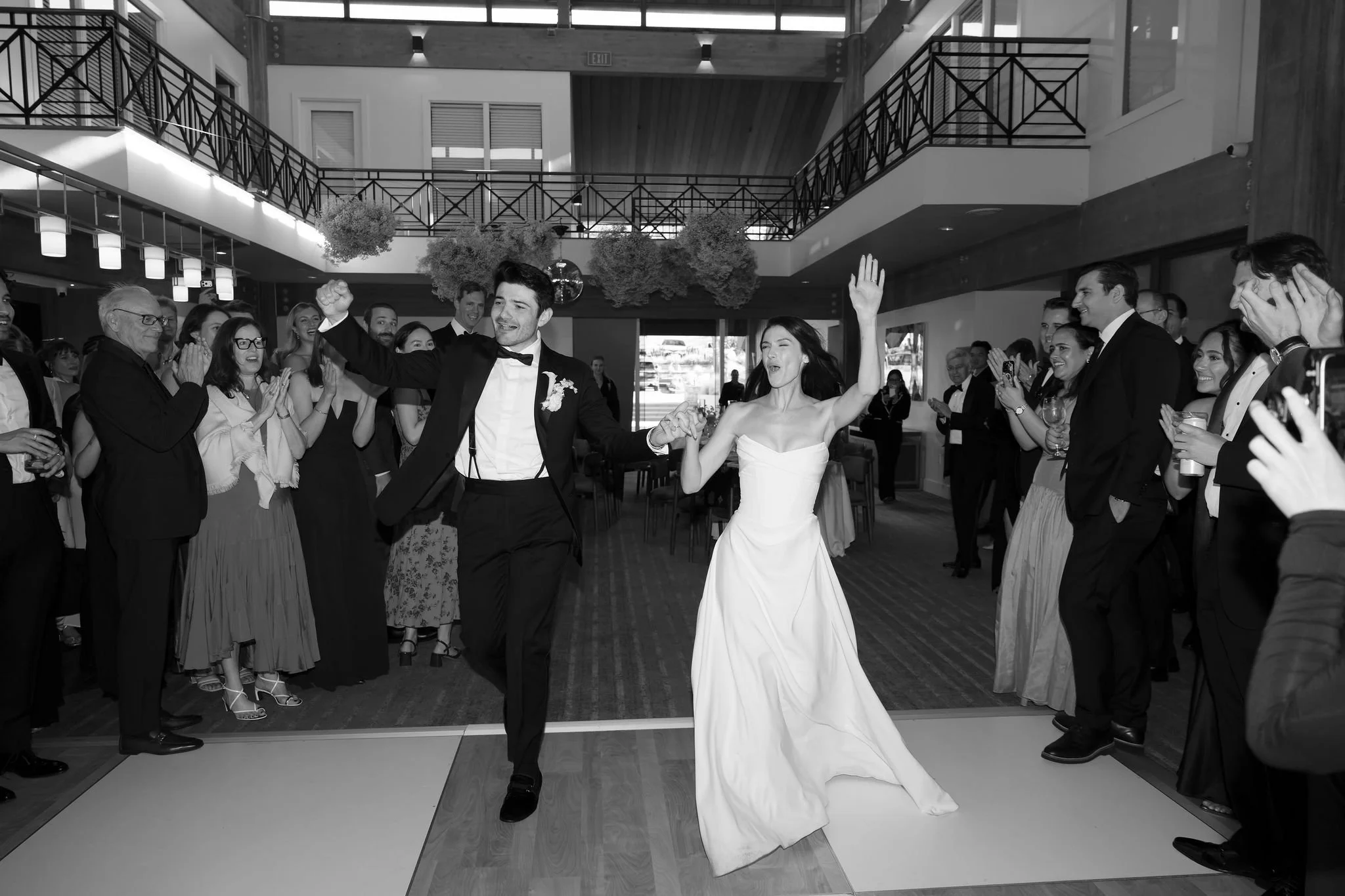 Newlywed couple dancing together surrounded by wedding guests during a joyful reception celebration.