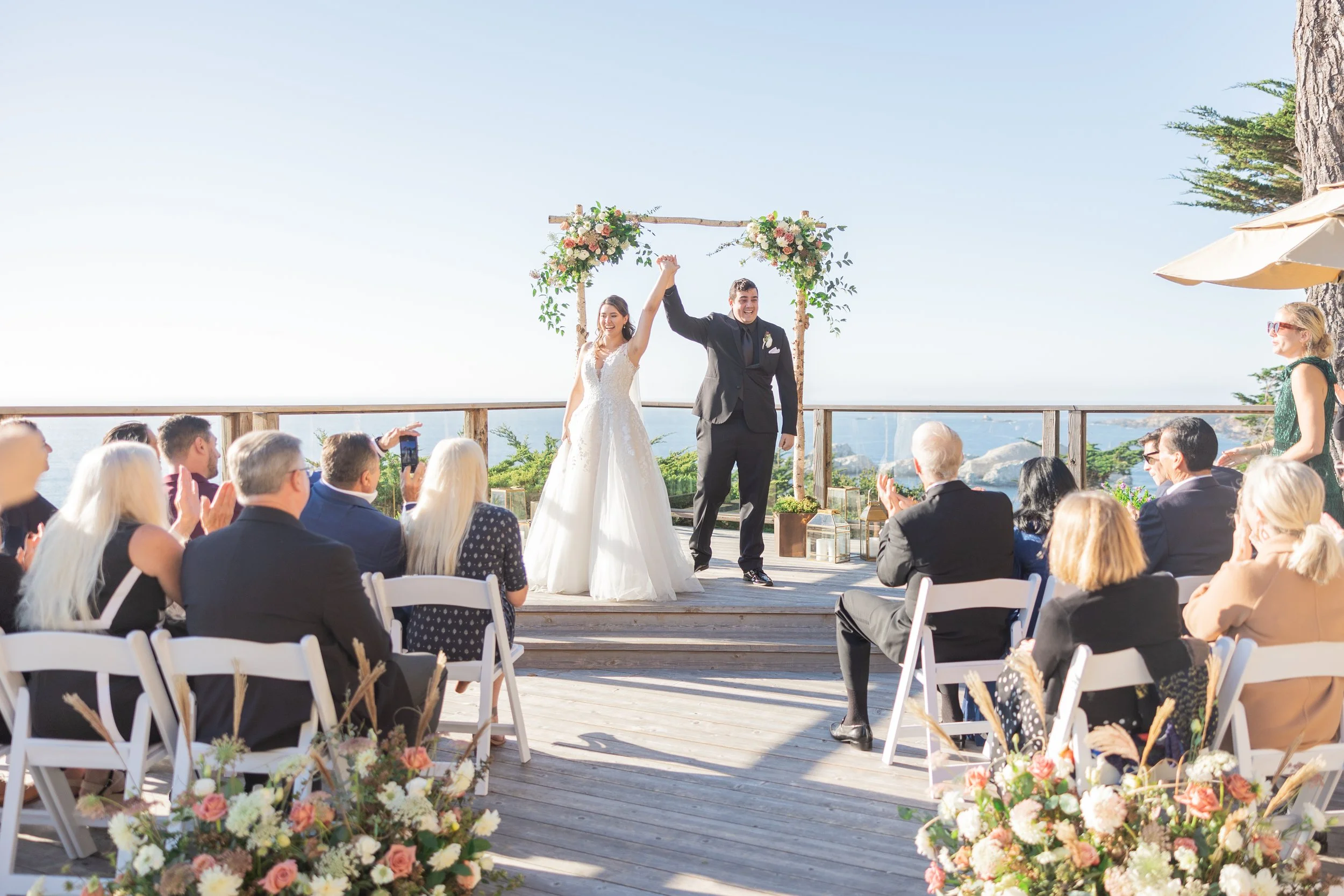Newlywed couple celebrating after their coastal wedding ceremony overlooking the Pacific Ocean