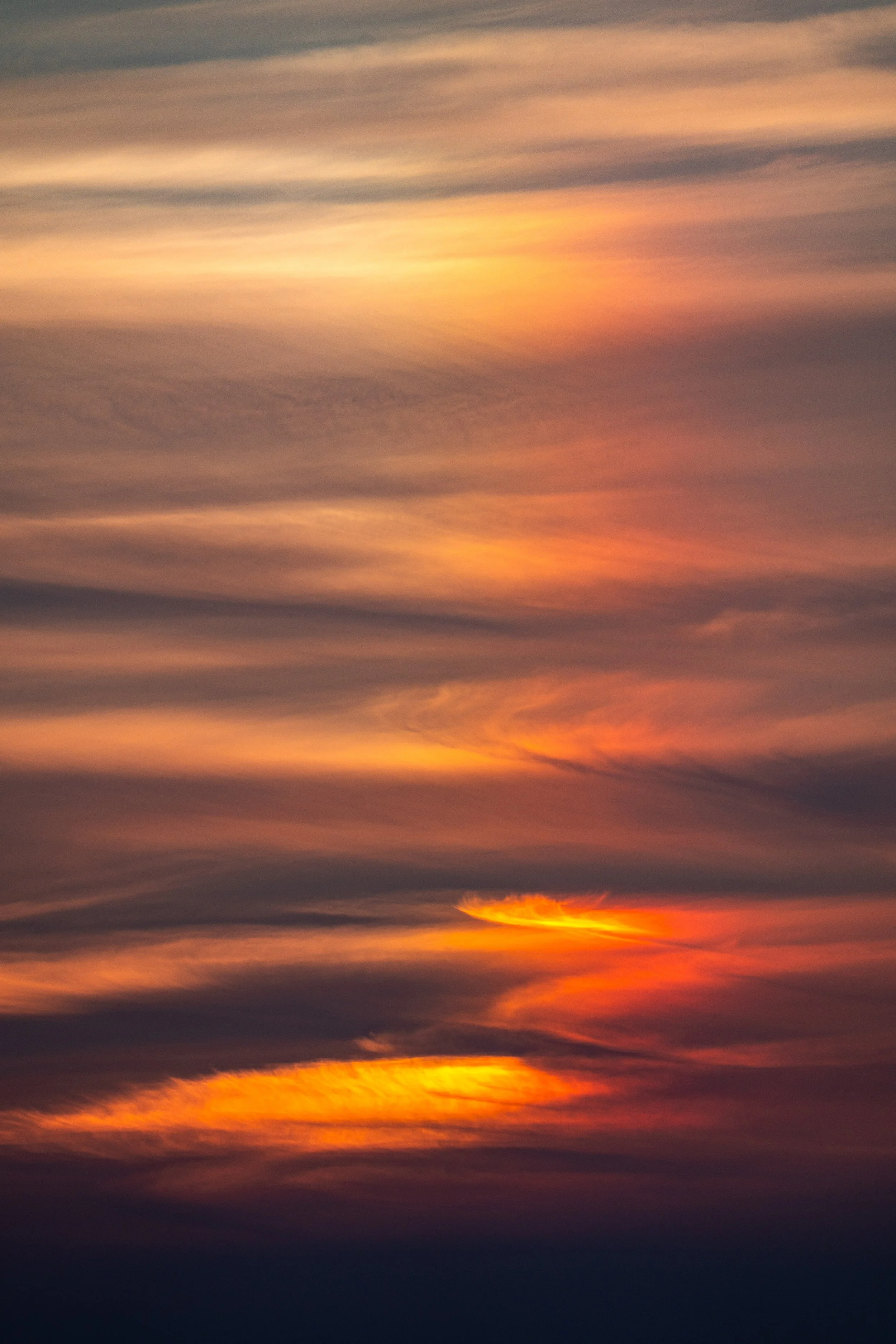 A colorful sunset with clouds in the sky, displaying shades of orange, yellow, pink, and purple.