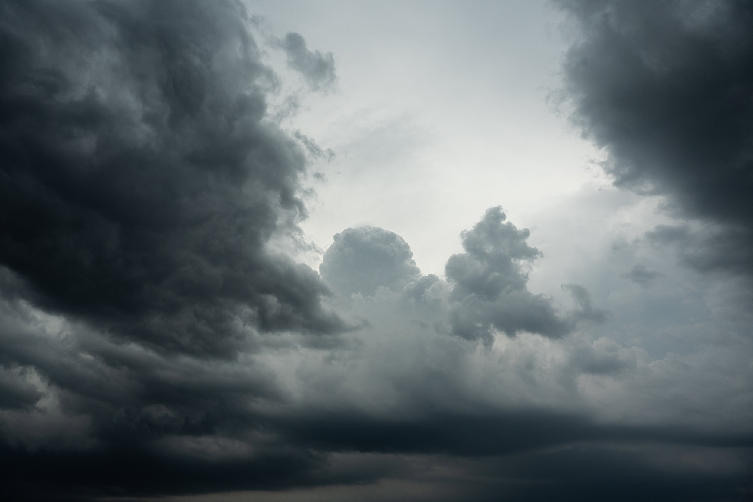Dark storm clouds covering the sky with a small clearing of lighter sky in the center.