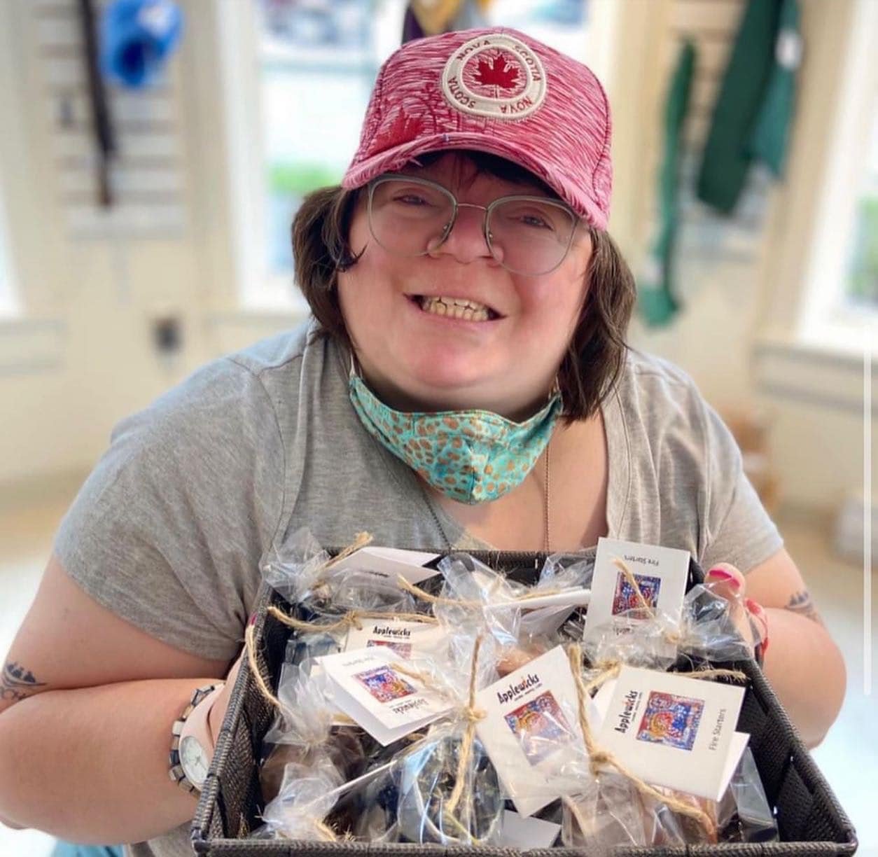 Woman smiling at the camera holding a basket of firestarters in the Applewicks store. (Copy)