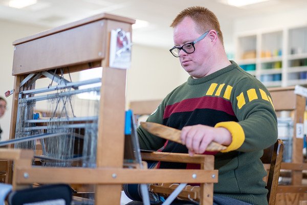 Man sitting at a weaving table making a bespoke weaving item. (Copy)