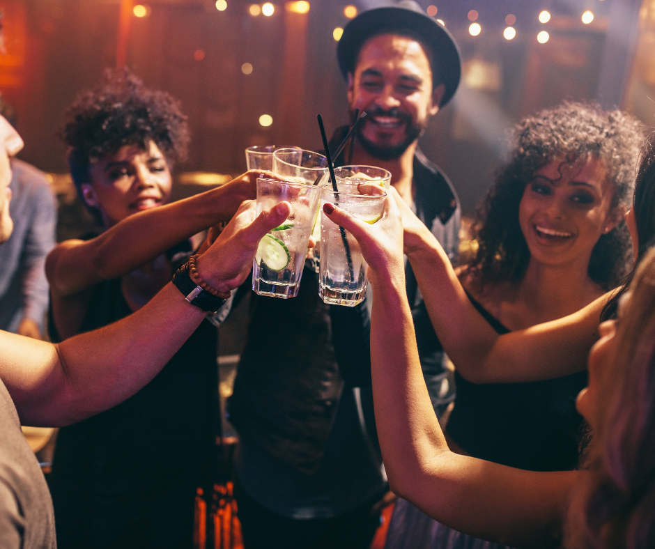 groups of friends out at night club in a circle toasting alcohol