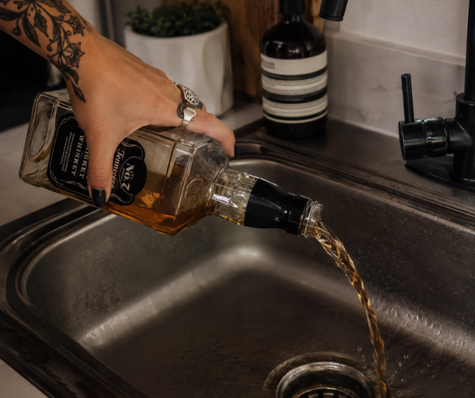 womans hand pouring liquor down sink