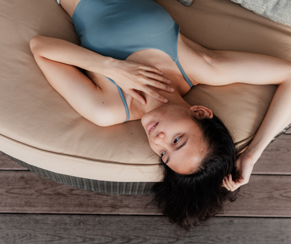 young ethnic woman laying down with blue tank top and hand on chest