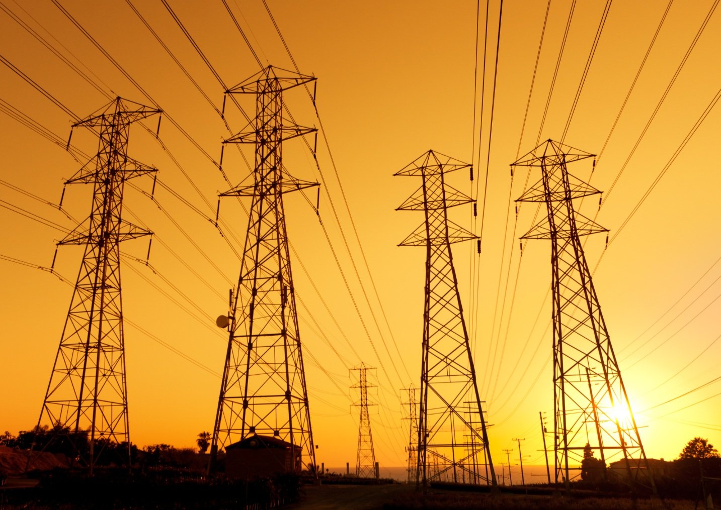 Four electricity masts in front of the setting sun