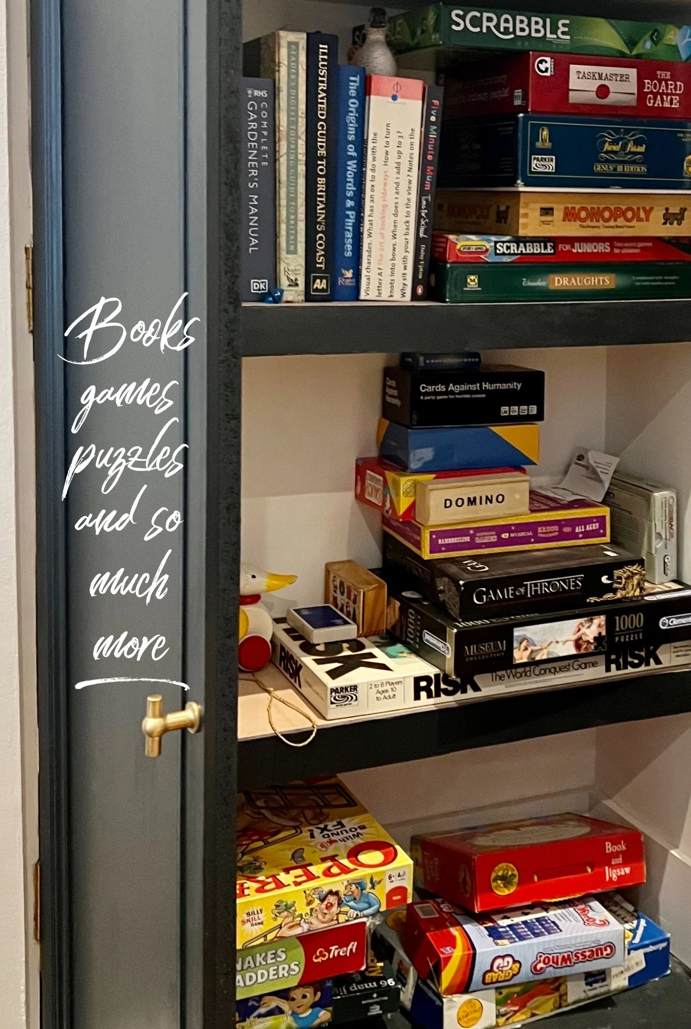 Books, board games, puzzles, and toys on shelves, including Scrabble, Monopoly, Risk, Game of Thrones, and others.