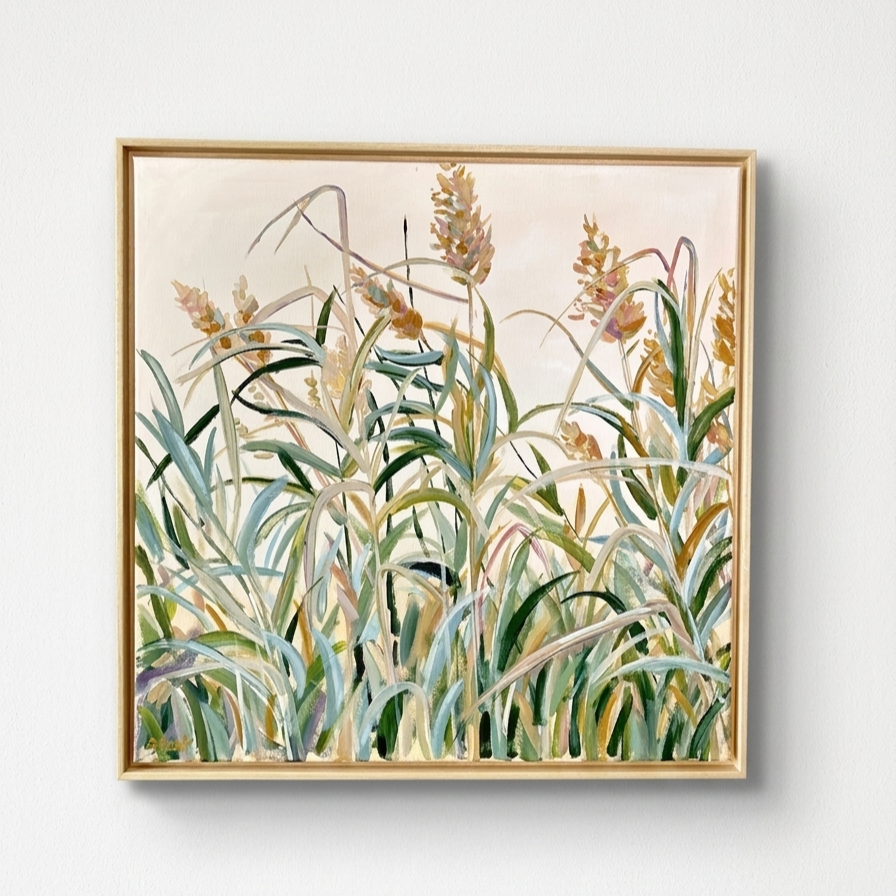 A framed painting of tall grass with flowers on a white wall.