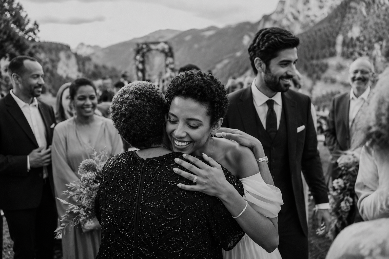 Bride hugging a wedding guest after an intimate ceremony in the Dolomites with family and friends celebrating nearby.