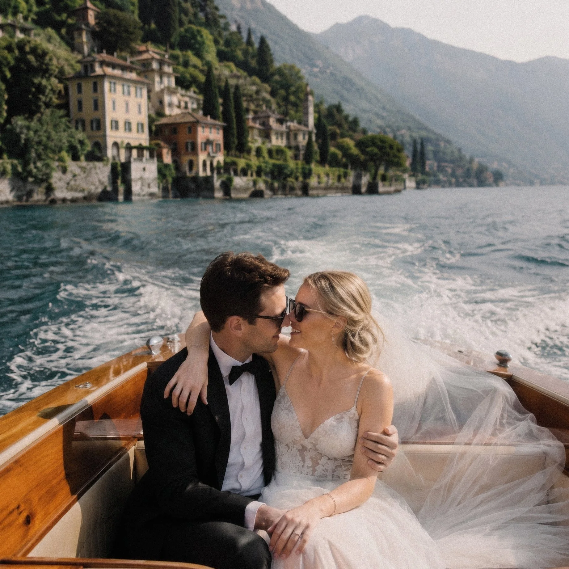 Bride and groom embracing on a classic wooden boat during a Lake Como wedding, cinematic destination wedding photography with dramatic mountain scenery and romantic Italian lakeside atmosphere