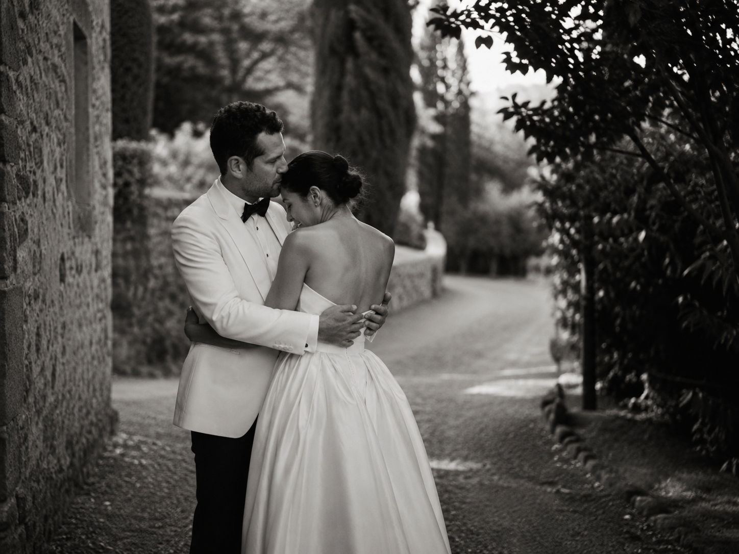 Black and white wedding portrait of a bride and groom embracing on a romantic stone pathway at Borgo Stomennano in Tuscany.