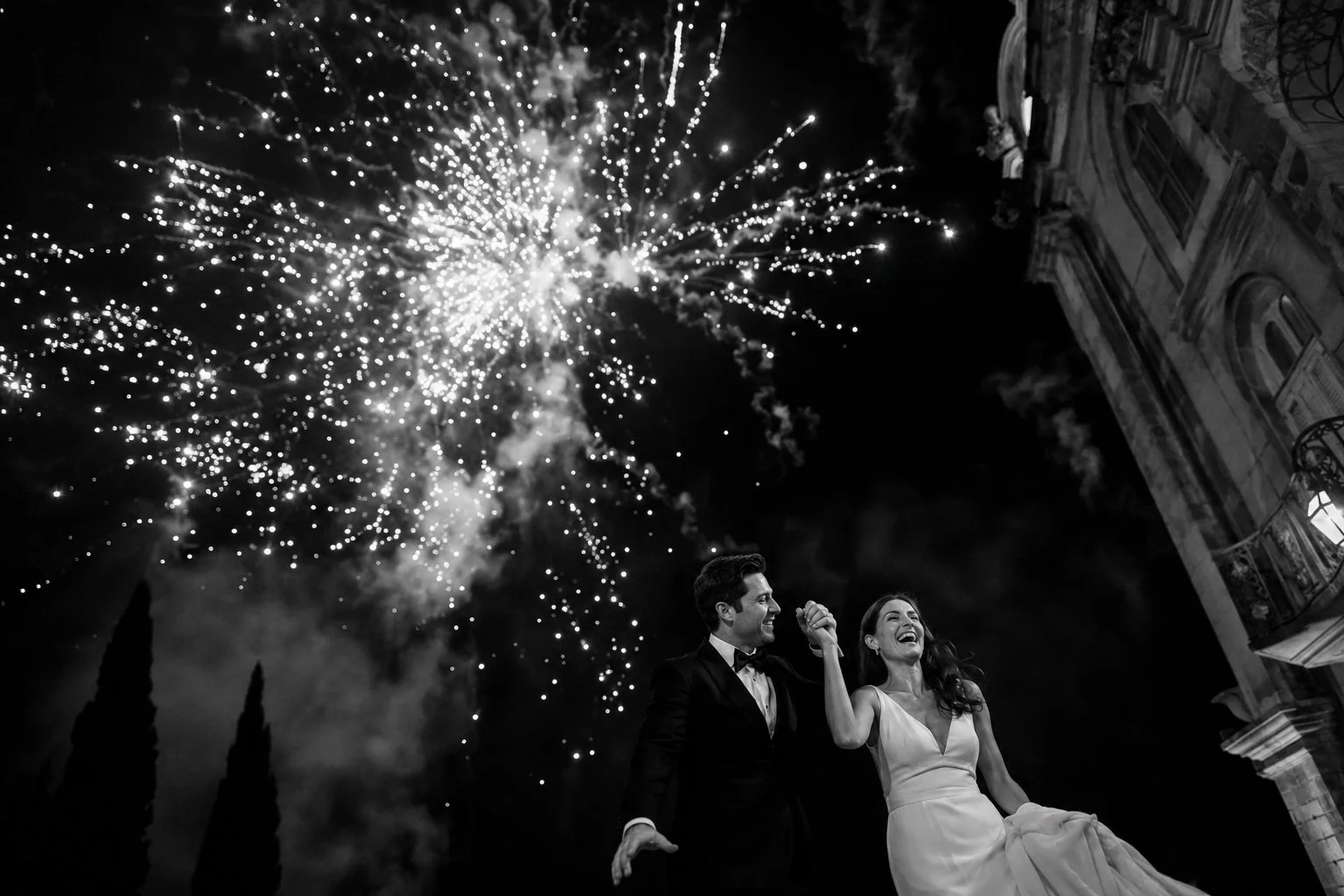 Bride and groom celebrating beneath fireworks during a luxury Lake Garda wedding reception at night.