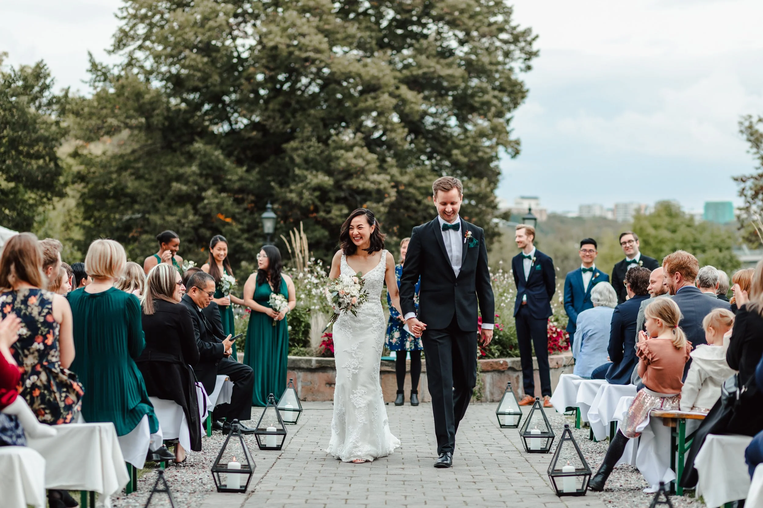 Bride and groom walking back down the aisle after an outdoor wedding ceremony surrounded by guests, elegant garden celebration with documentary-style emotion and natural movement.
