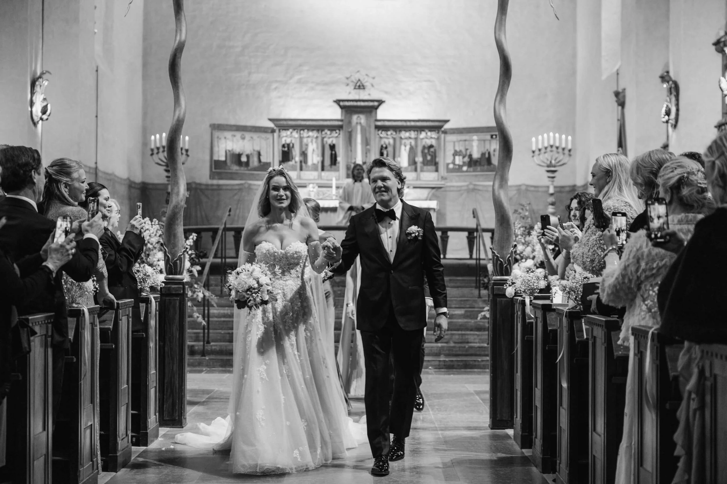 Newlyweds walking together down the aisle after their Högalidskyrkan wedding ceremony