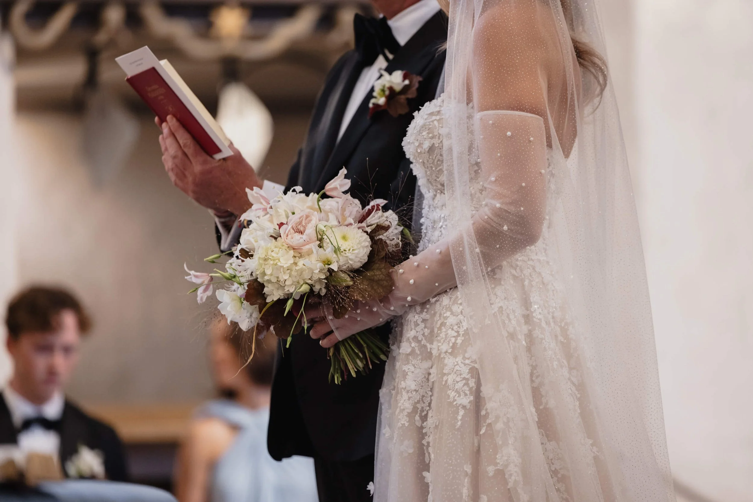 Bride holding her bouquet beside the groom during a Stockholm church wedding