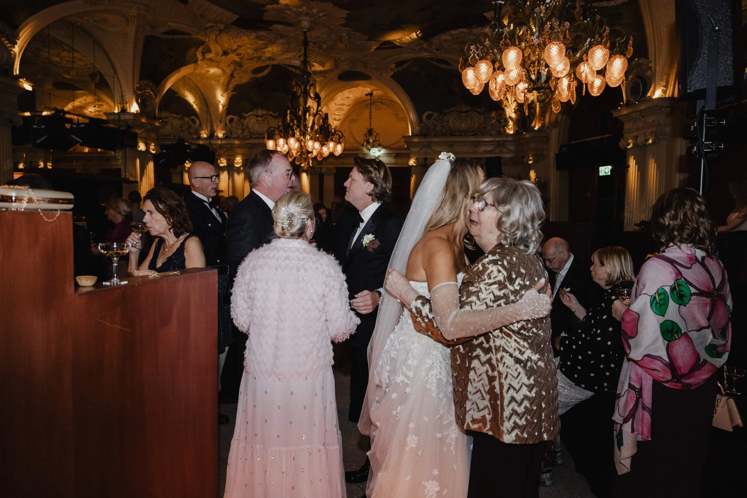 Bride embracing a guest during a documentary wedding reception at Café Opera