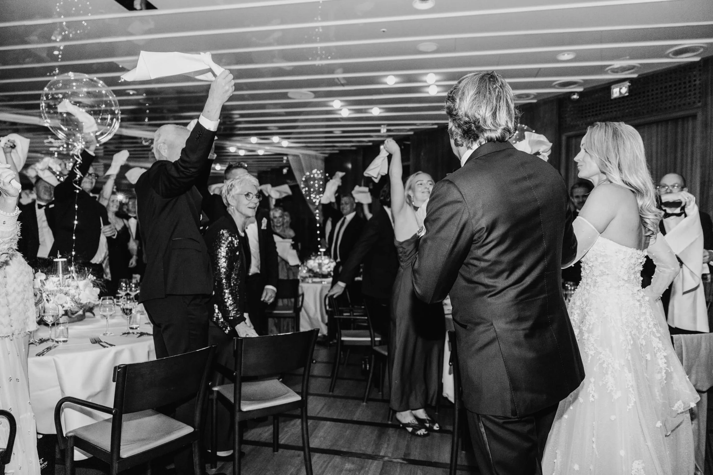 Couple and guests waving napkins during an energetic Café Opera wedding dinner
