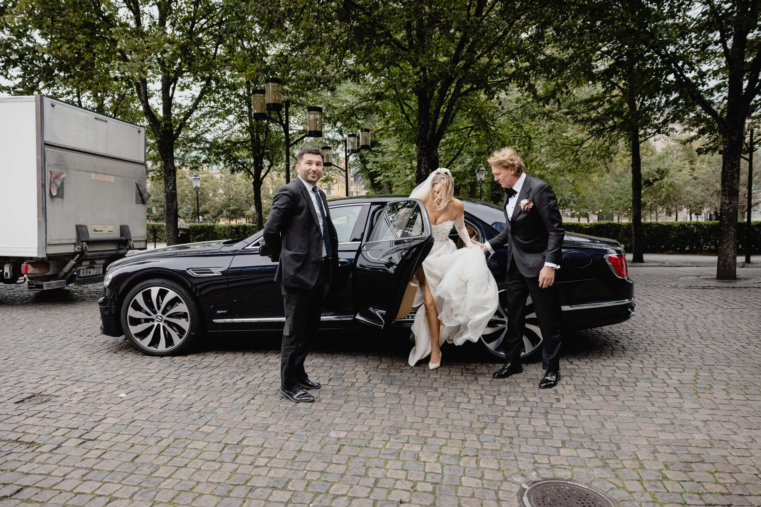 Bride stepping from a chauffeur-driven car with the groom as they arrive at Café Opera