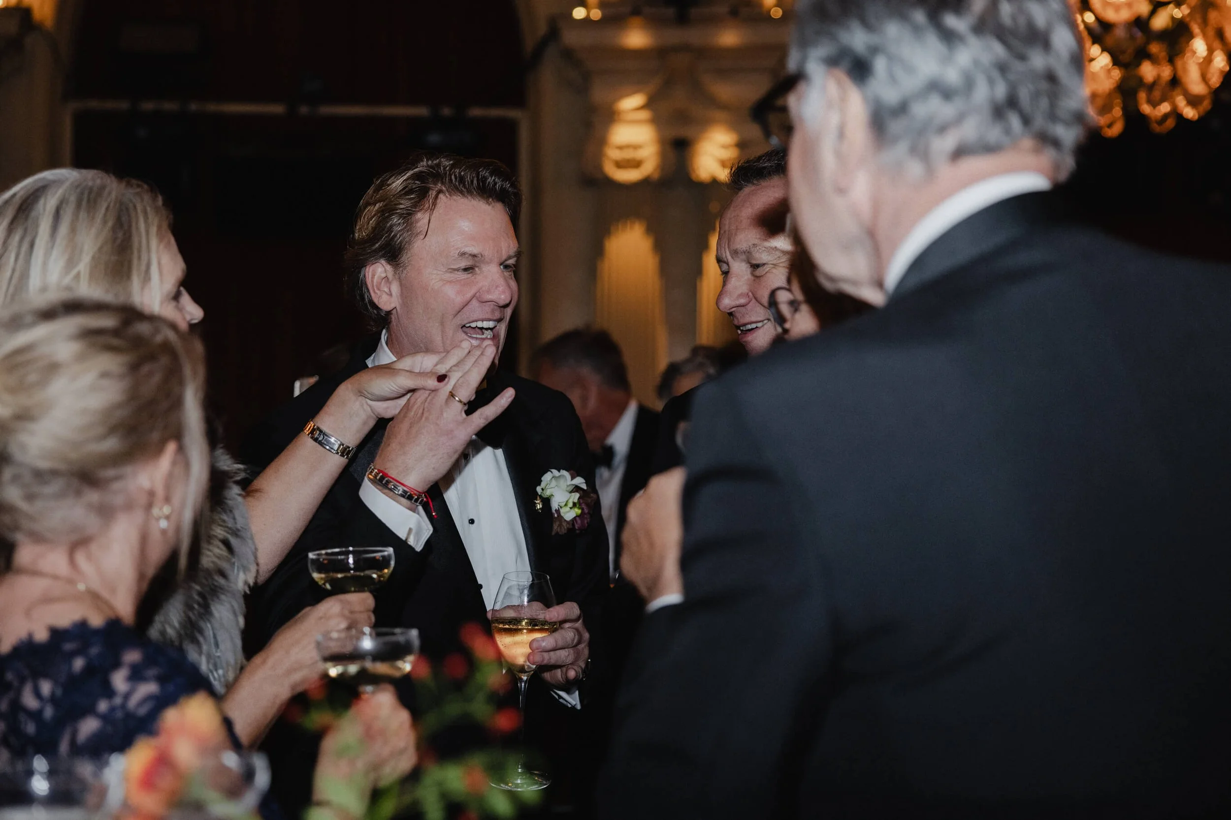 Groom laughing with friends during an international wedding reception at Café Opera