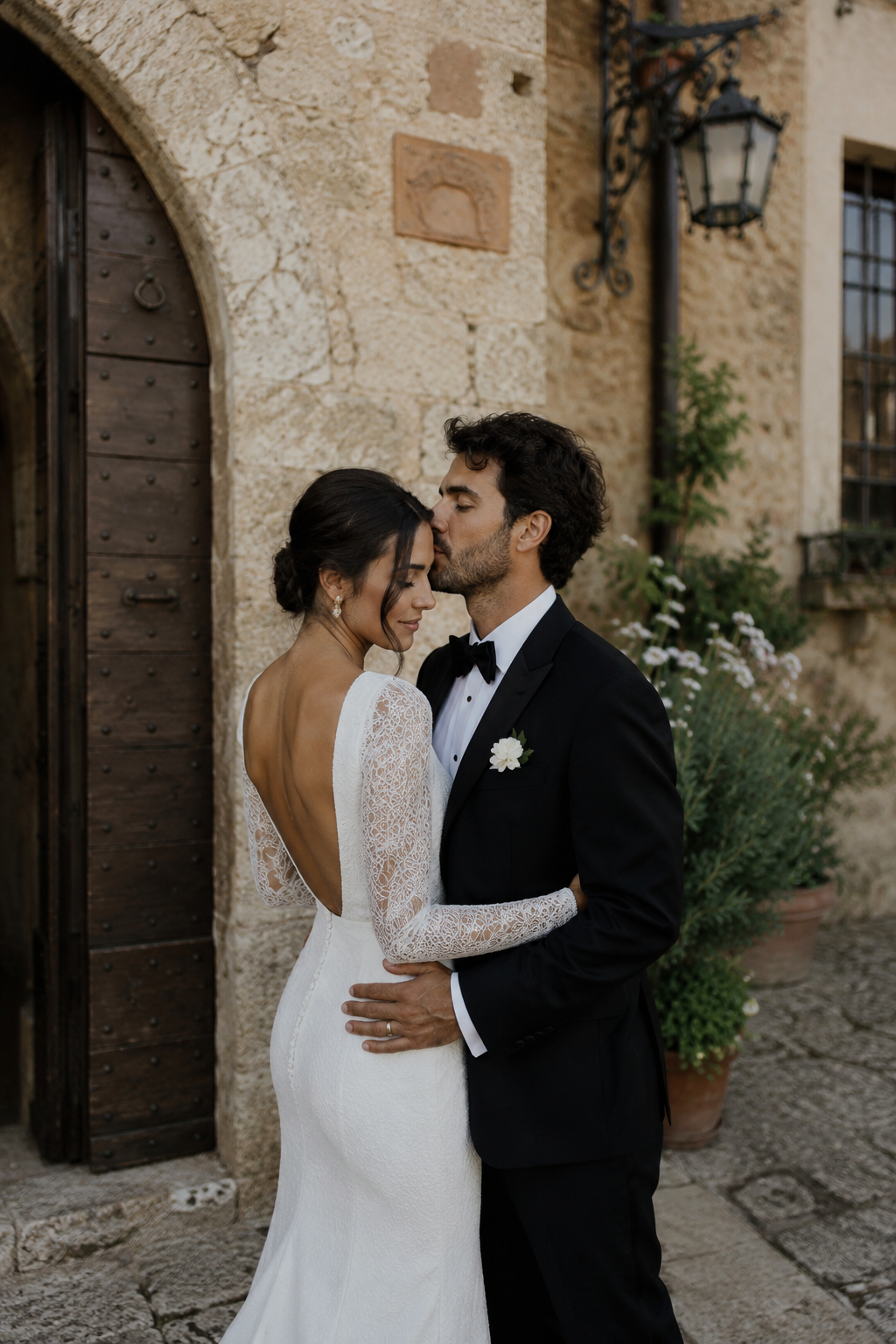 Romantic Tuscany wedding portrait of bride and groom embracing in a historic Italian village with rustic stone walls and warm evening light, documentary style destination wedding photography in Tuscany by WeddingStudio.se