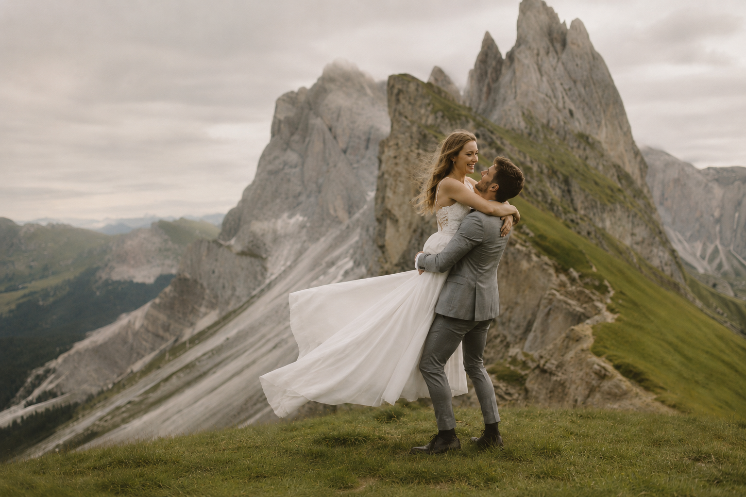 Bride and groom embracing on the mountain ridges of Seceda in Val Gardena, surrounded by the dramatic Odle peaks and soft cinematic light during an adventurous Dolomites wedding photo session.
